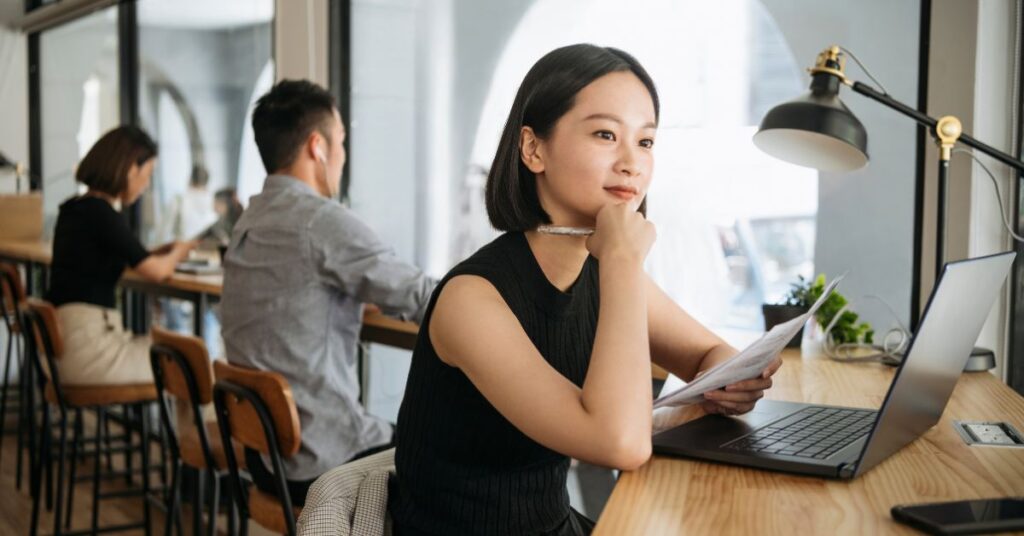 businesswoman working from a coworking office. Sitting by the window stool and looking at her laptop.