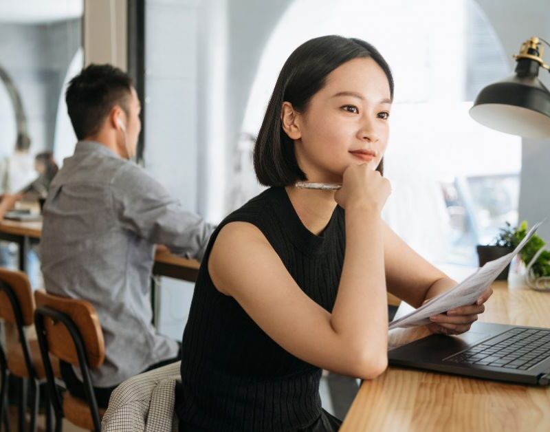 businesswoman working from a coworking office. Sitting by the window stool and looking at her laptop.