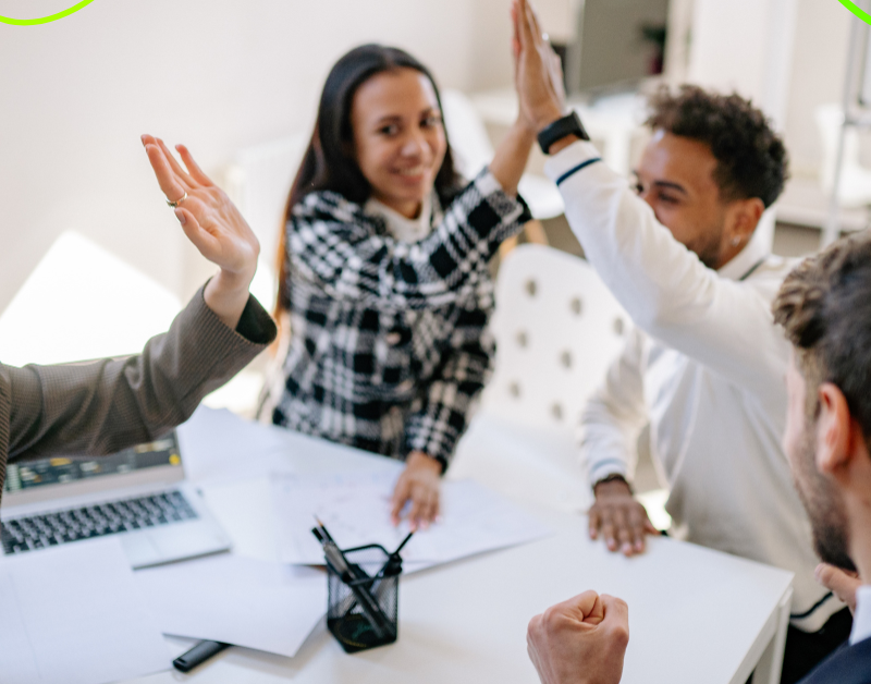 group of coworkers feeling happy and accomplished. working in a meeting room. high fiving one another.