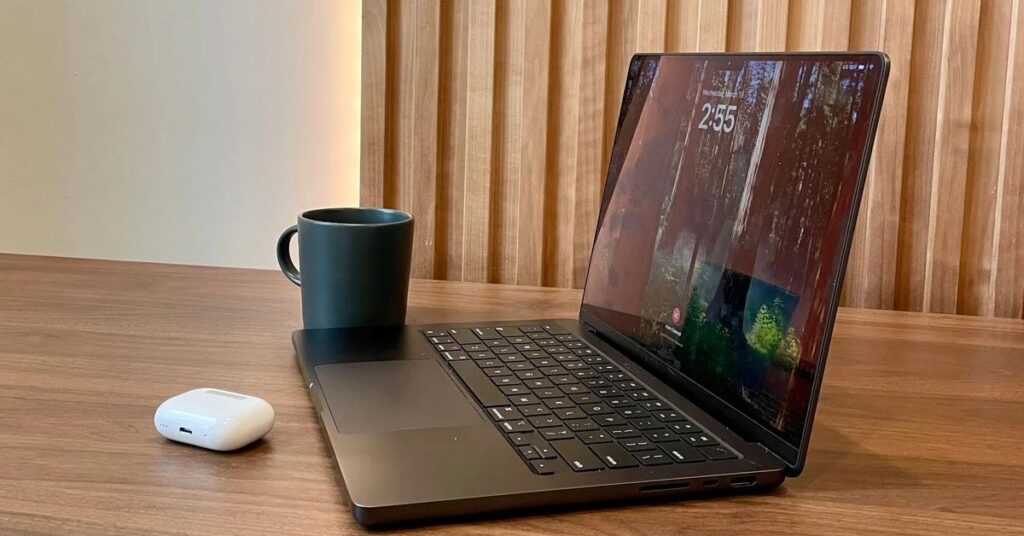 close up of a laptop and a coffee mug and a pair of wireless headphones on one of our open coworking spaces at Brick & Mortar