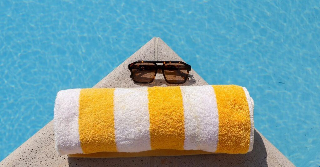a picture of a yellow and white beach towel with sunglasses representing Summer Work-From-Home Distractions