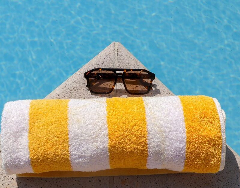 a picture of a yellow and white beach towel with sunglasses representing Summer Work-From-Home Distractions