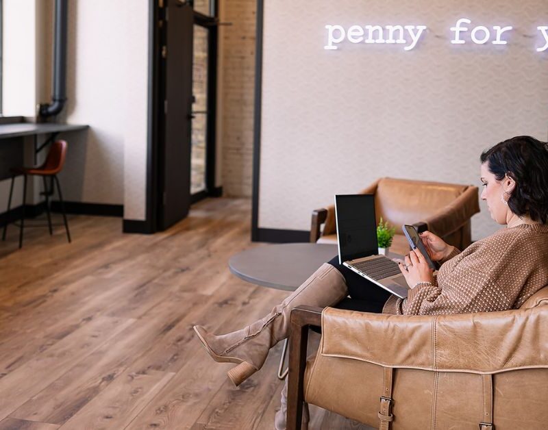 woman sitting in a brick and mortar working on her laptop and using the The 2-Minute Reset guide That Instantly Improves Focus